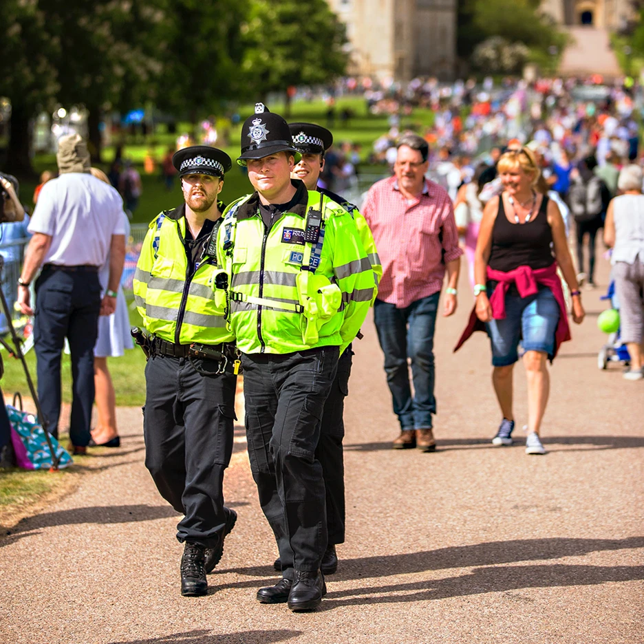 Three police officers walking in a crowded street.