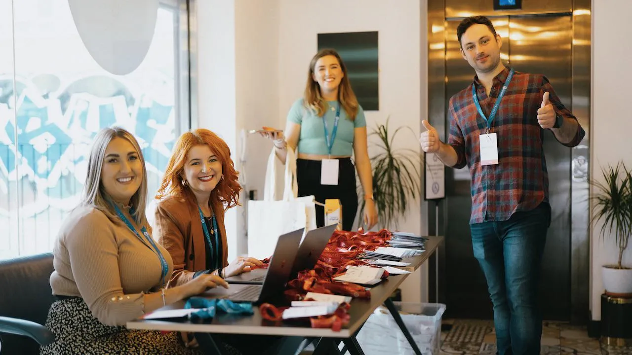 4 members of the Zengenti team smiling at the welcome registration desk at Velocity 2023.